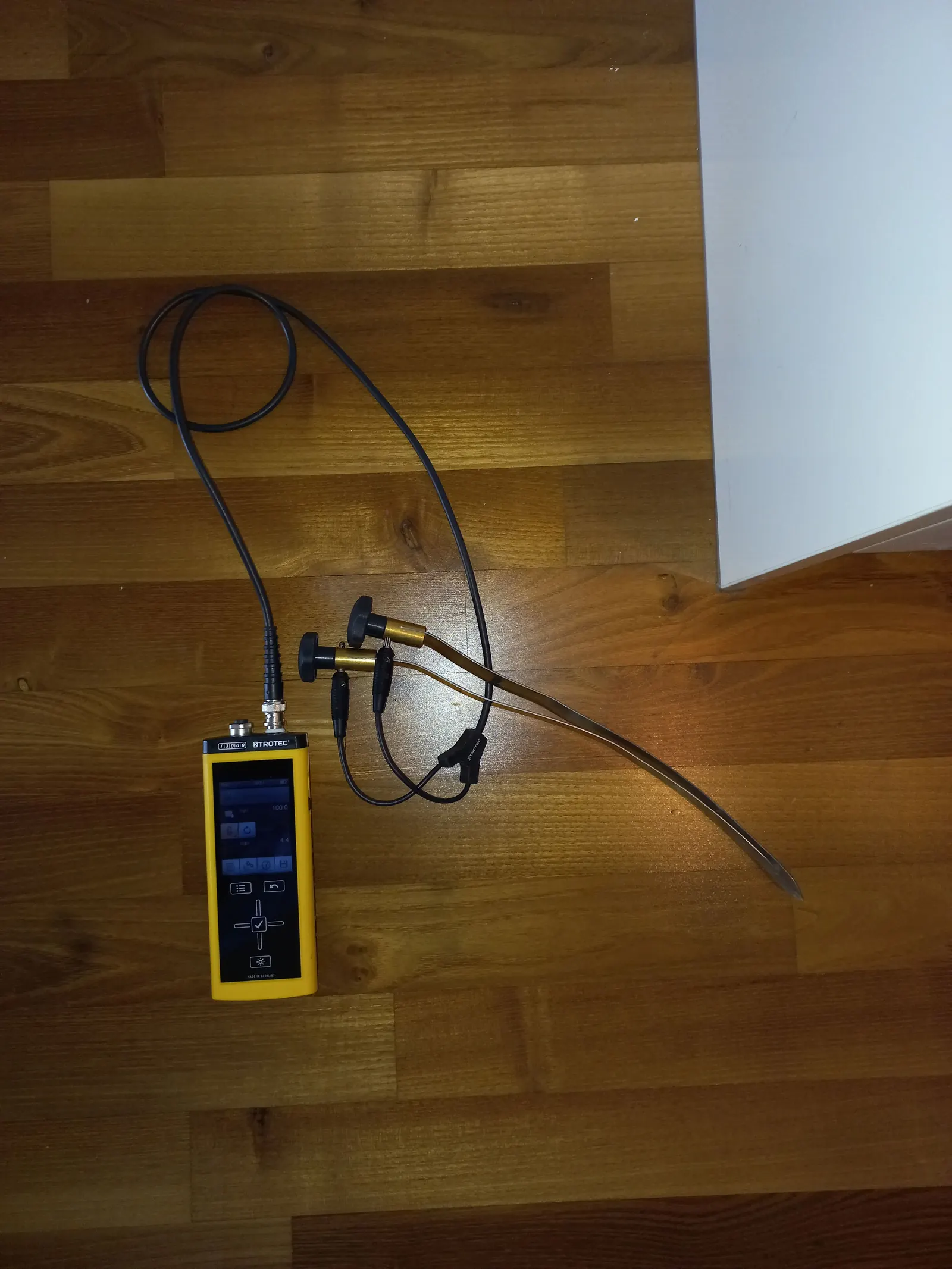Moisture meter probes testing a floor for hidden water during slab leak detection in a Lancaster, CA home