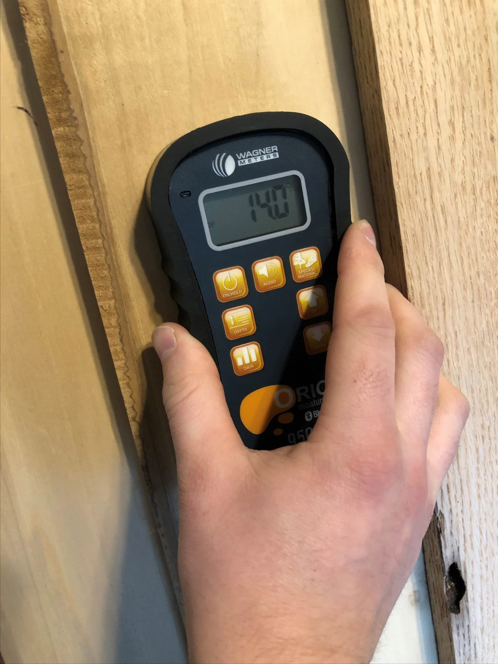 Handheld moisture meter pressed against wood during a mold inspection in a Lancaster, CA home
